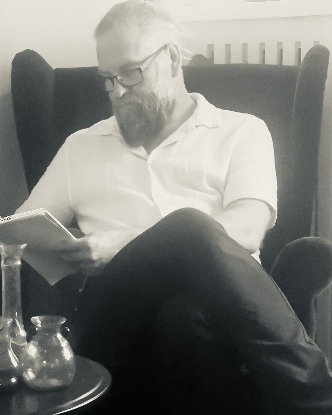 Andreas Lundin sitter i en fåtölj och antecknar i ett block